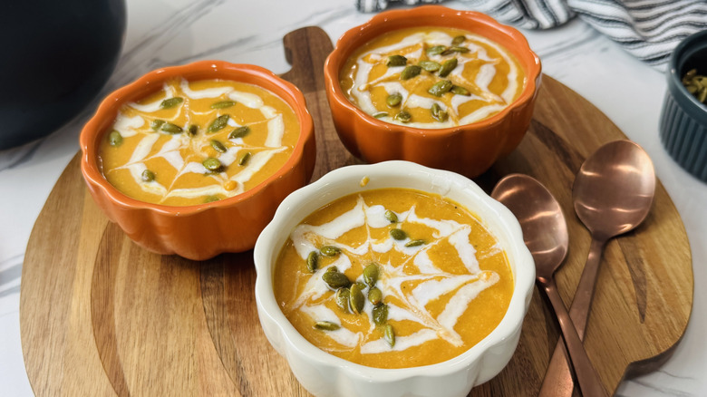 Bowls of pumpkin soup with spiderweb design and pepita garnish