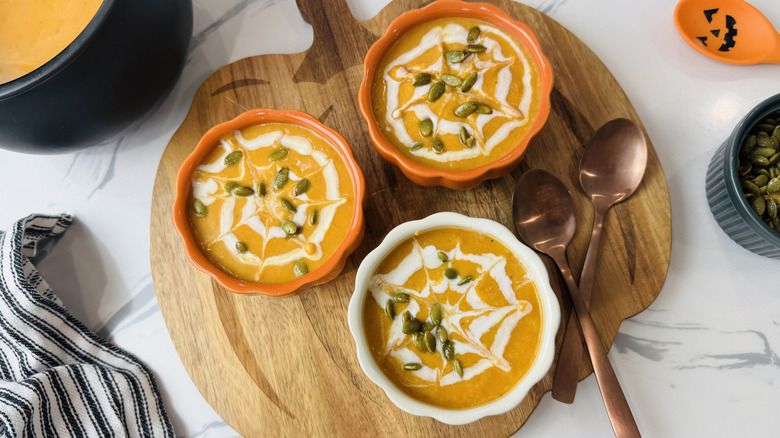 Bowls of pumpkin soup with spiderweb design and pepita garnish
