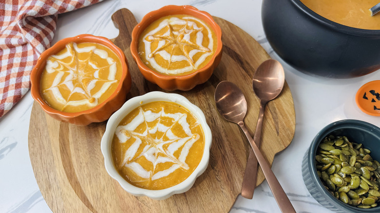 Bowls of pumpkin soup with coconut milk spiderweb designs