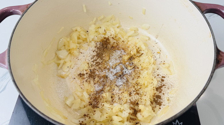 Diced onion topped with various spices in large pot