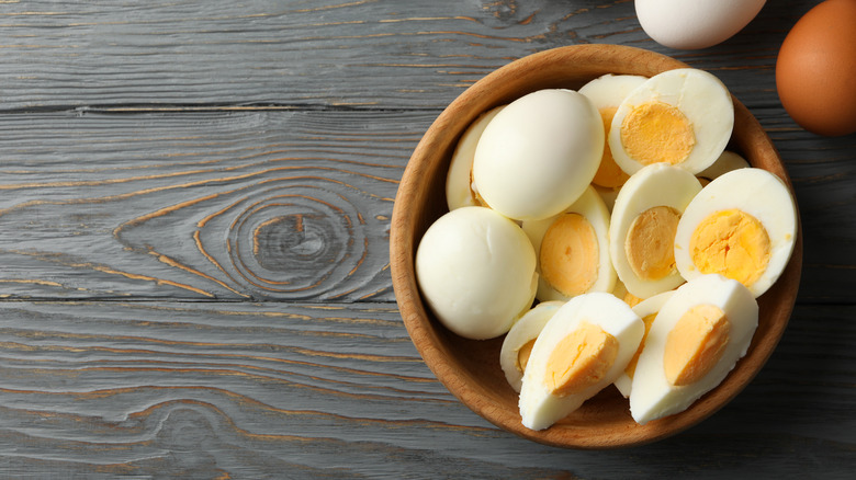 Hard-boiled eggs in a bowl on wooden background