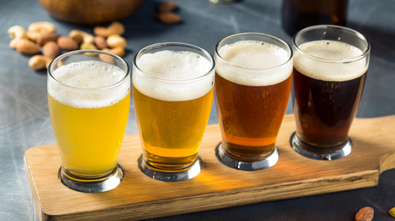 A beer flight of four beers from lightest to darkest, with nuts in the background.