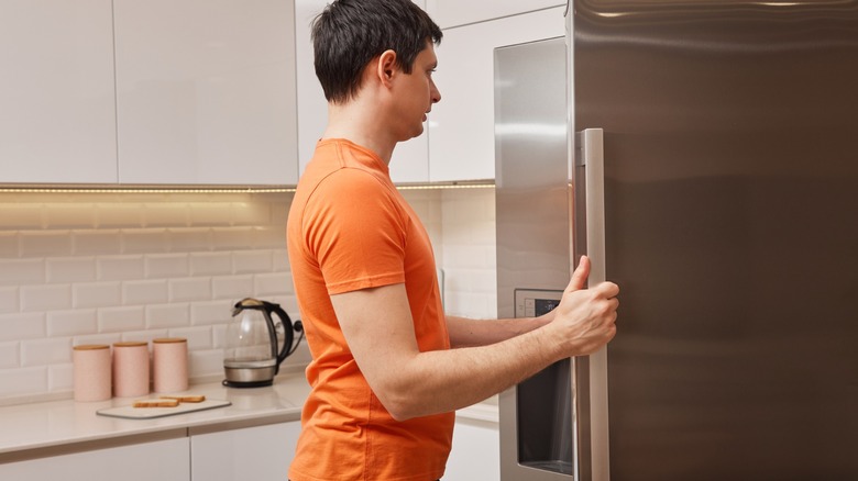 man opens fridge in kitchen