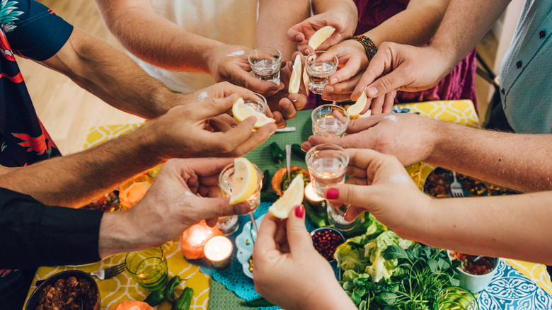 Guests around a table holding shots of tequila