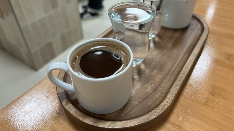 cup of black coffee and water glass on tray