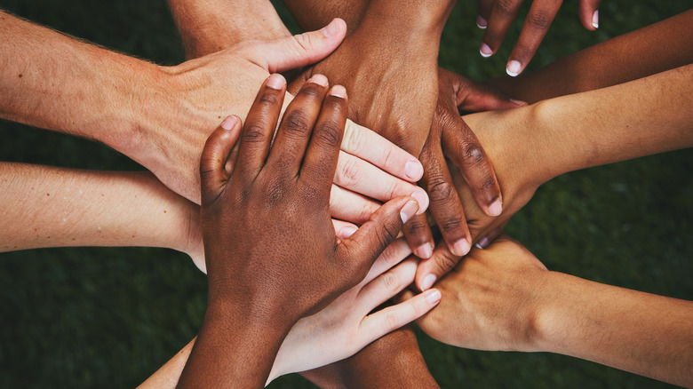 Hands stacked on top of each other in a pile.