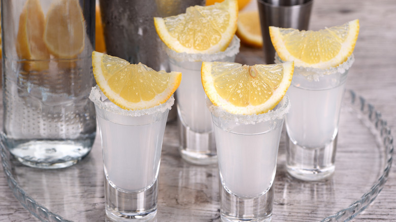 Fresh lemons and lemon juice paired with vodka in a shot.