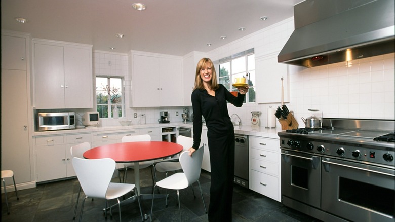 a woman lifts a yellow mug in an 80s kitchen