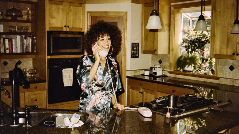 woman with a landline phone in an '80s-styled kitchen