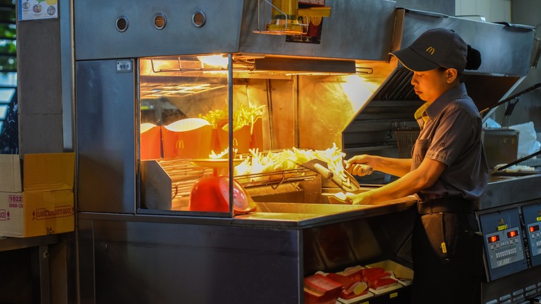 mcdonald's employee scoops fries in restaurant kitchen