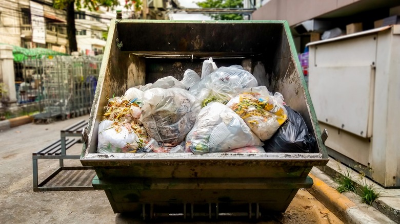 immense garbage bin/dumpster is full of trash