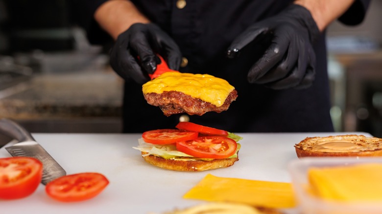 chef with black gloves assembles a burger