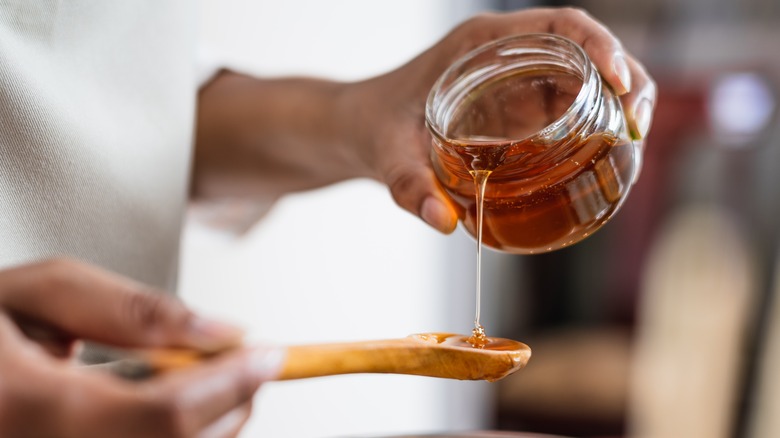 Hand pouring honey onto spoon