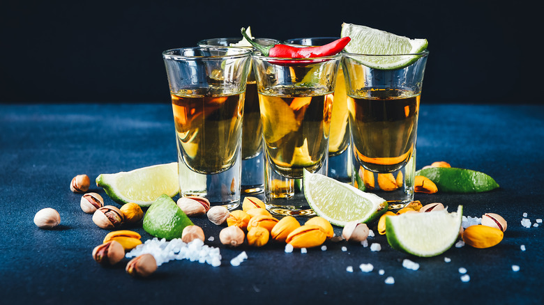 Tequila shots with chili pepper, lime wedges, nuts and salt
