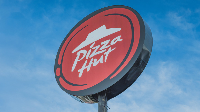 Pizza hut sign outside restaurant against blue sky