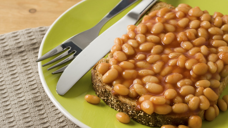 Beans on toast on a plate with a fork and knife