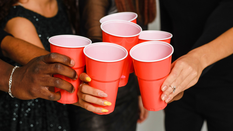 people holding up red solo cups