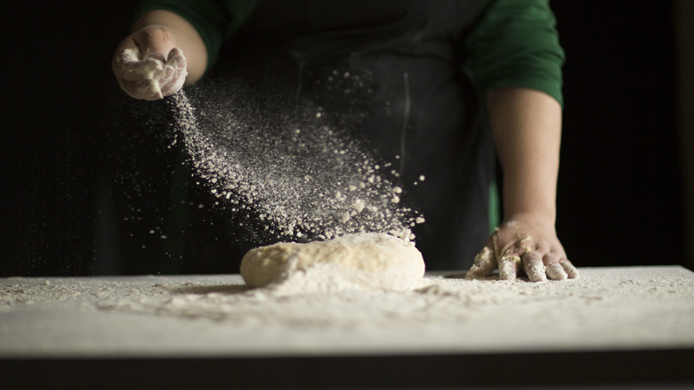 baker dusting bread with flour