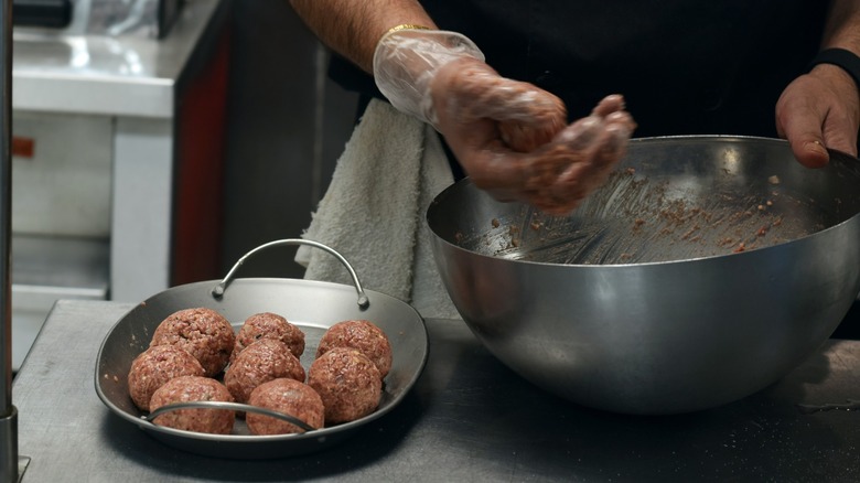 hands manipulate ground beef into patties