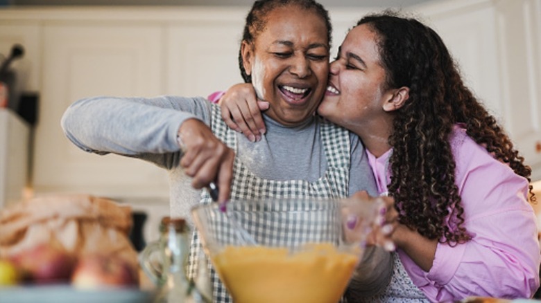 older woman shows young woman how to cook