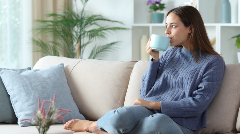 woman drinks a cup of coffee on couch