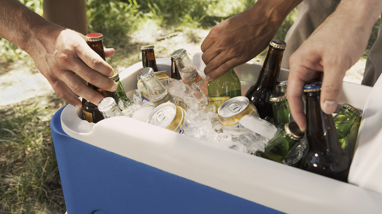 hands grabbing beers, cooler