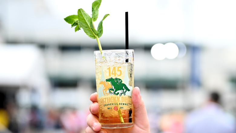 hand holding a mint julep in a decorative Kentucky derby glass