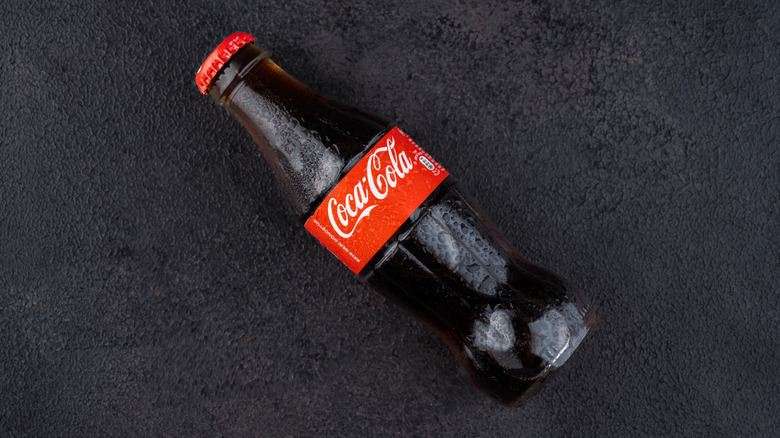 Glass bottle of Coca-Cola on dark surface