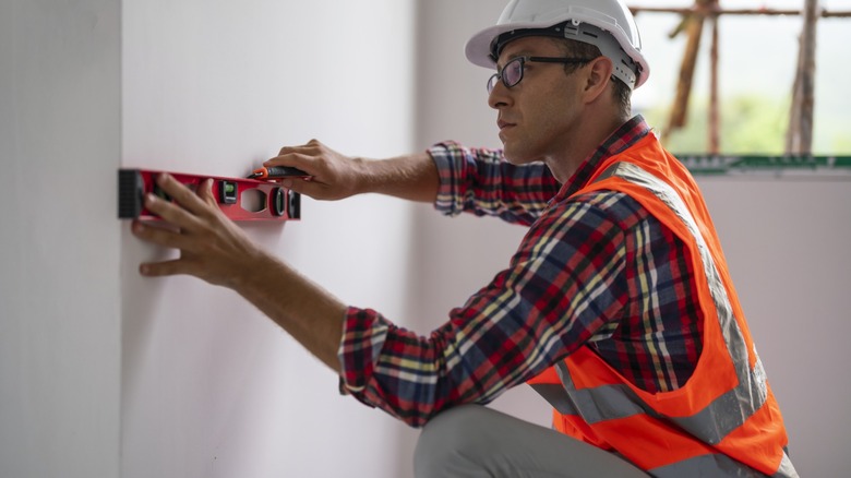 man in hard hat works with level