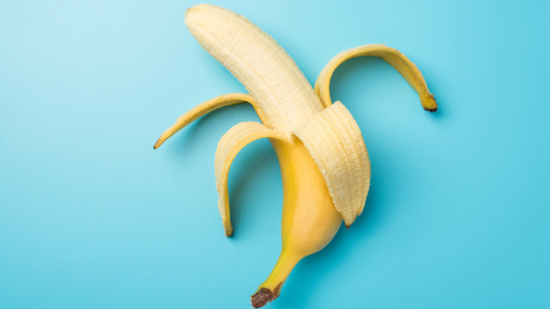 single half-peeled banana on a light blue background