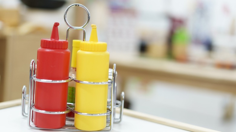 ketchup and mustard bottles in a rack on a table