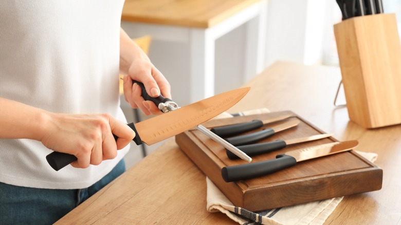 woman honing a large knife in home kitchen