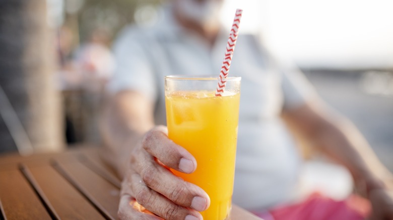 hand holds glass of orange juice