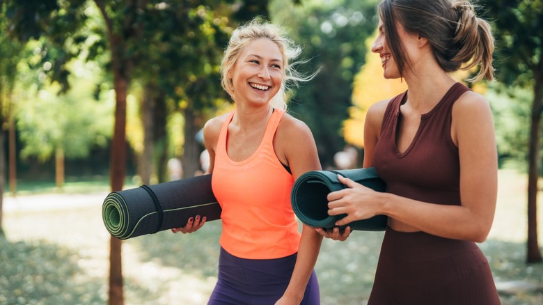 two sporty women carry yoga mats