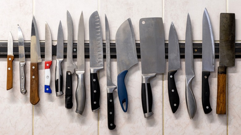 Various knives on magnetic knife holder attached to wall