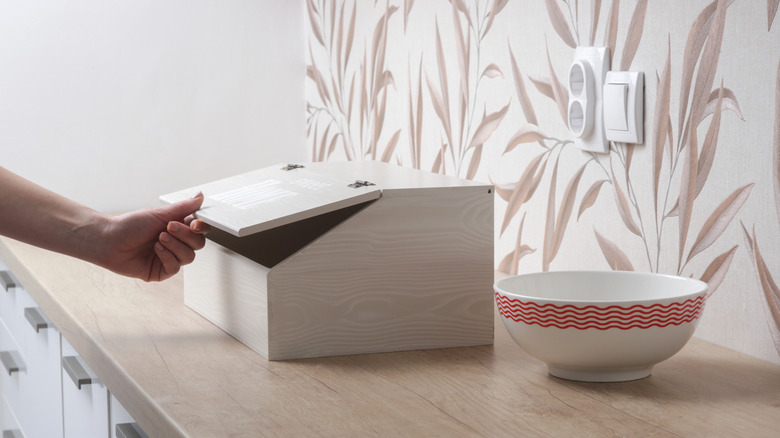 hand opening bread box on counter