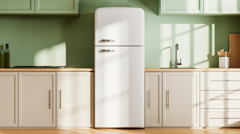 A white fridge between kitchen cabinets