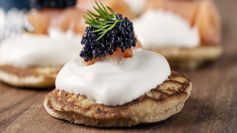 Closeup of blinis topped with creme fraiche, smoked salmon, and caviar.