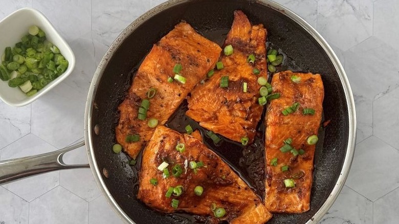 Salmon filets in pan with chopped scallions