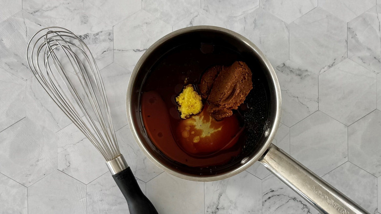 Miso glaze ingredients in saucepan next to whisk
