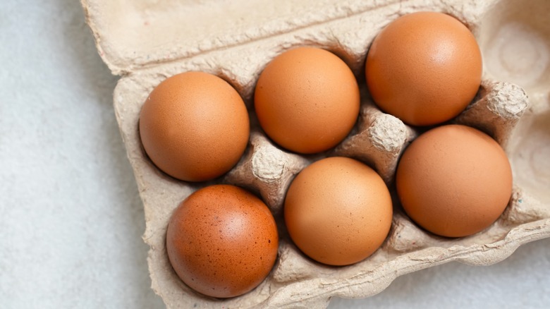 half a dozen brown eggs in a carton
