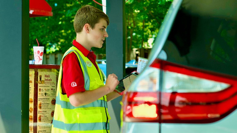 young employee takes order in chick fil a drive thru