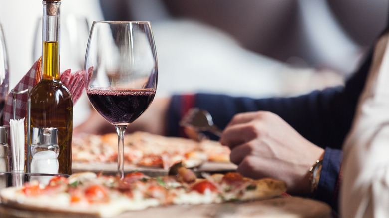person eating pizza with wine