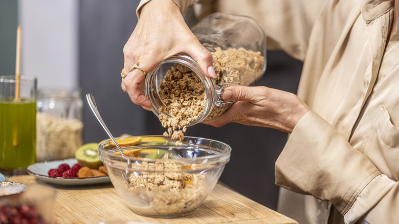Someone pouring oats from a jar into a bowl