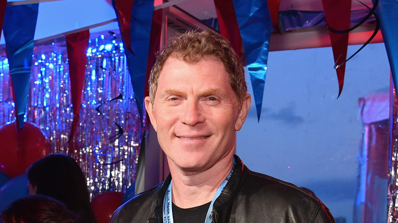 Bobby Flay smiling while wearing black leather jacket.