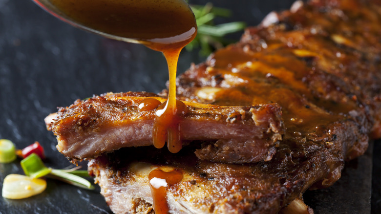 Drizzling BBQ sauce on ribs.