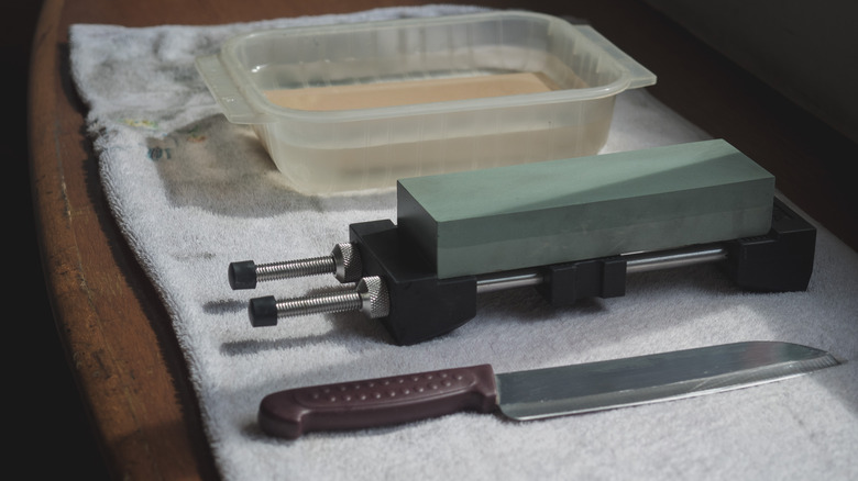 Whetstones, a holder, a knife and a towel on a wooden surface 