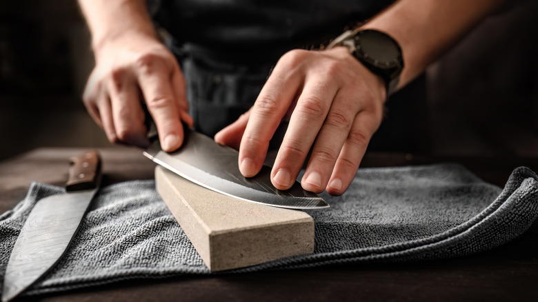 Man sharpening knife on a whetstone