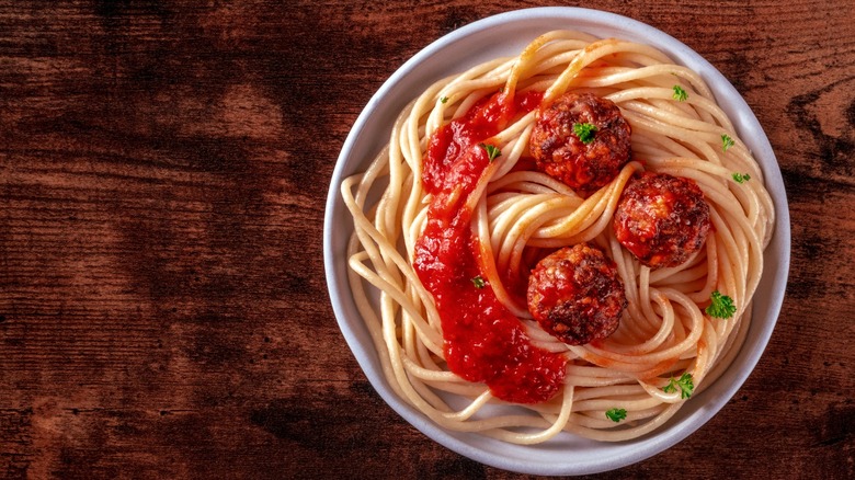 Spaghetti and meatballs with tomato sauce in white bowl