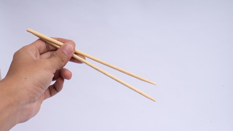 A close-up of someone's hand holding chopsticks in the traditional position